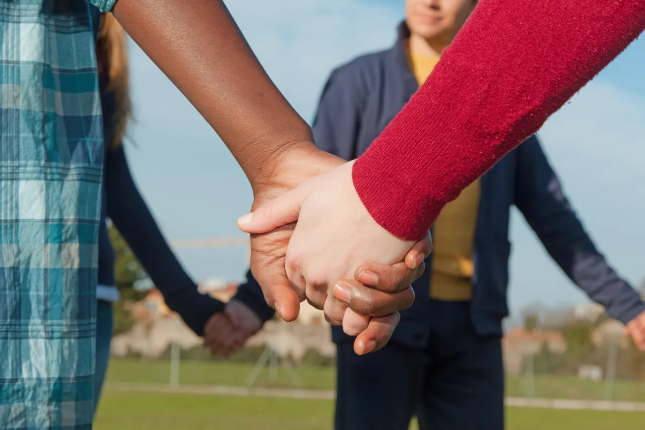 Diverse group of people holding hands in a circle outdoors