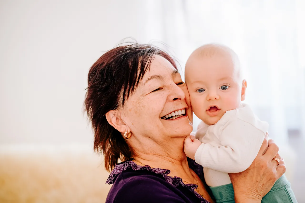 Older woman smiling while holding a baby